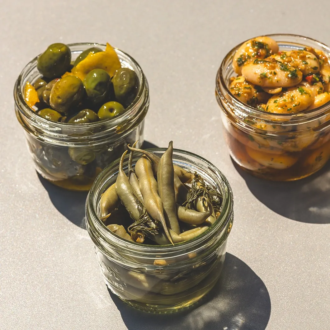 snack jars full of marinated gigante beans, pickled green beans, and olives